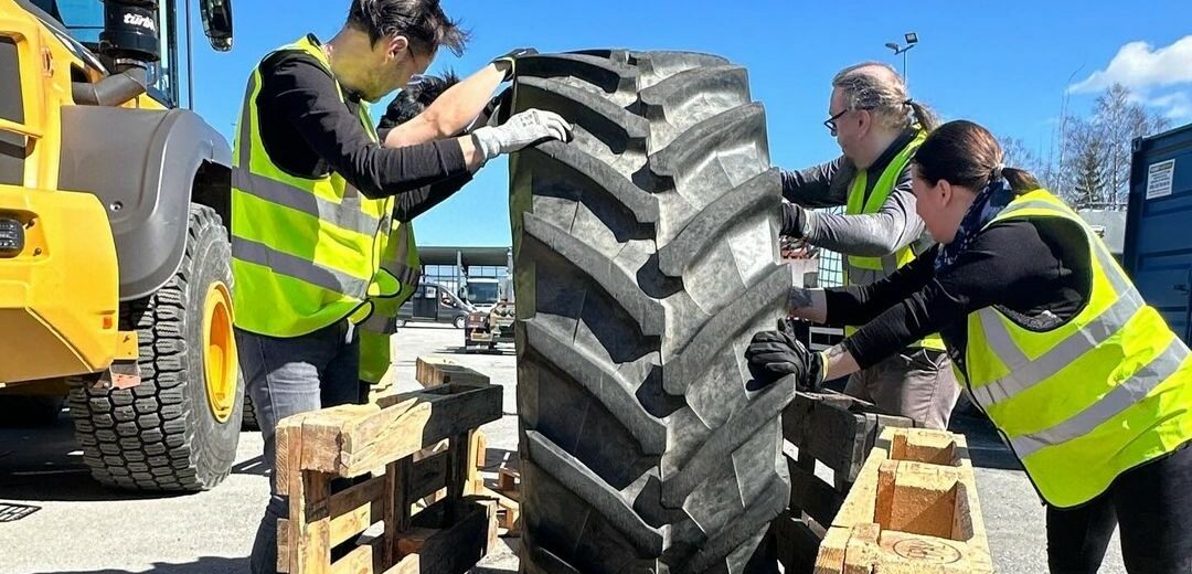 Tredun opiskelijat siirtävät traktorinrengasta.