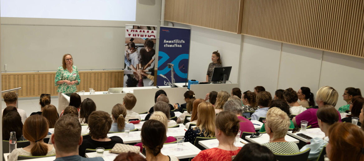 Susanna Kangas juontamassa tilaisuutta täydessä auditoriossa