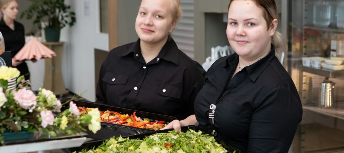 Kaksi Tredun ravintola- ja catering-alan opiskelijaa hymyilee kameralle.