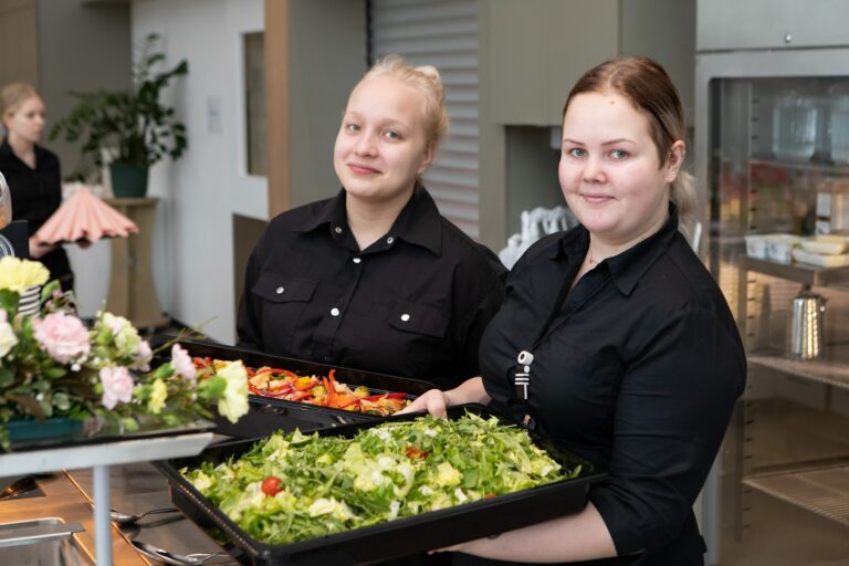 Kaksi Tredun ravintola- ja catering-alan opiskelijaa hymyilee kameralle.